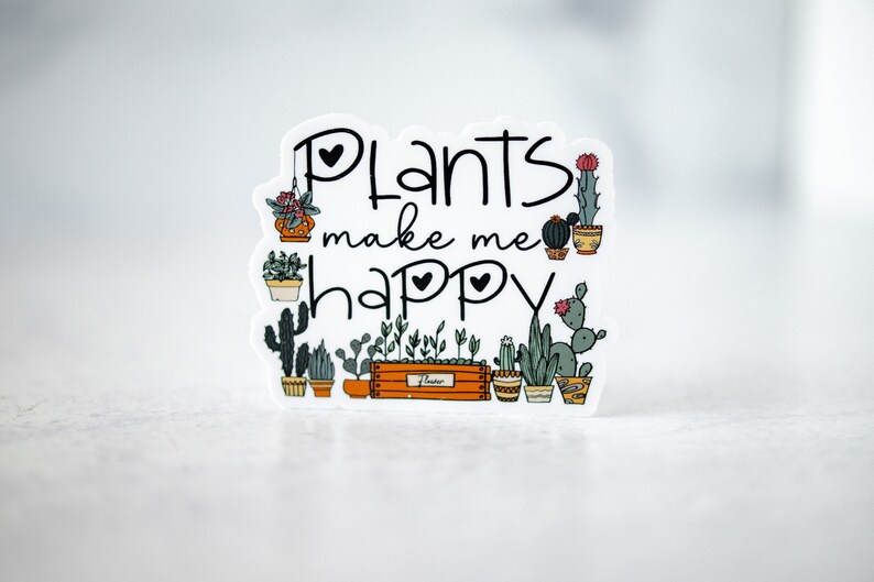 May include: White sticker with the text "Plants make me happy" in black lettering with two small hearts. The sticker features a variety of potted plants and cacti in a row.