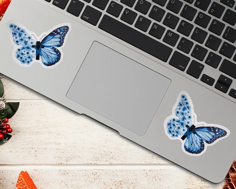 May include: Two blue butterfly stickers on a silver laptop. The butterflies are made of blue flowers and have a black ribbon in the center.
