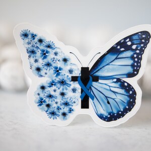 May include: A blue butterfly with a blue ribbon and a black cross in the center. One wing is made of blue flowers.