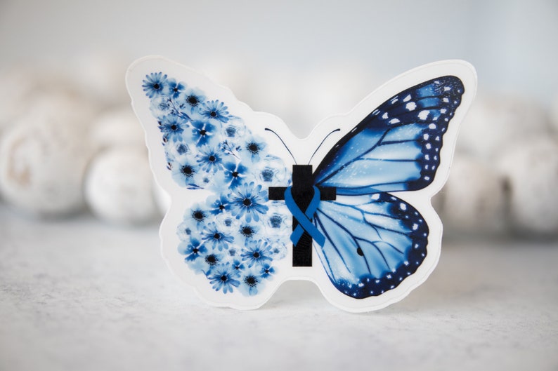 May include: A blue butterfly with a blue ribbon and a black cross in the center. One wing is made of blue flowers.