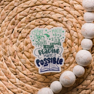 Puede incluir: Una pegatina blanca con texto verde y azul que dice "Science Matters, Math Counts, But Reading Makes It Possible". La pegatina presenta un s&iacute;mbolo de &aacute;tomo y un libro.