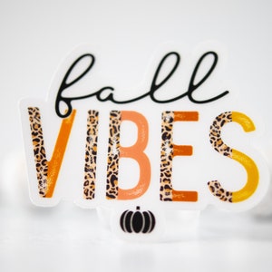 K&ouml;nnte beinhalten: Aufkleber "Fall Vibes" mit Leopardenmuster in Orange, Gelb und Schwarz. Der Aufkleber zeigt den Text "fall vibes" mit einer kleinen K&uuml;rbisgrafik darunter.
