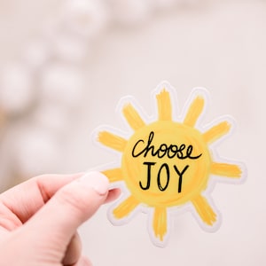 May include: A yellow sun sticker with the words "Choose Joy" written in black.