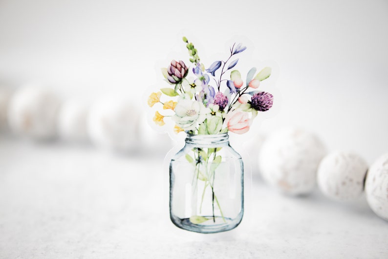 May include: A watercolor illustration of a bouquet of flowers in a clear glass jar. The flowers are in shades of purple, pink, yellow, and white.