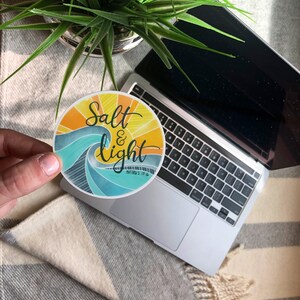 May include: A round sticker with a blue and yellow wave design. The sticker says "Salt & Light" with the scripture reference "Matthew 5:13-16" underneath.