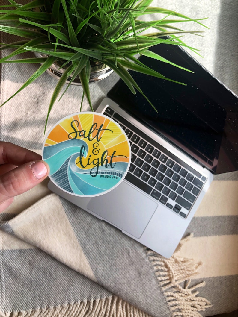 May include: A round sticker with a blue and yellow wave design. The sticker says "Salt & Light" with the scripture reference "Matthew 5:13-16" underneath.