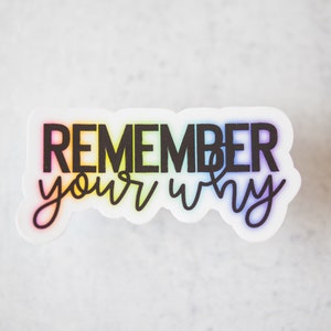 May include: A white sticker with a rainbow gradient background and black text that reads "REMEMBER your why".