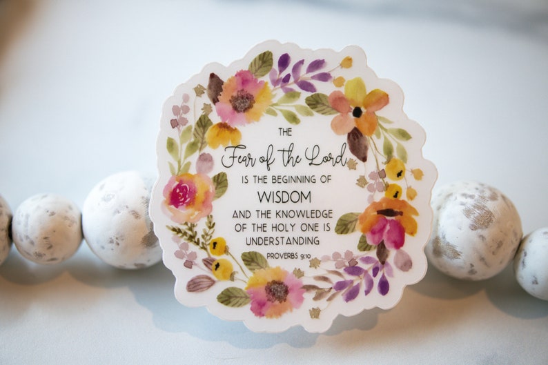 May include: A white sticker with a watercolour floral wreath surrounding the text "THE Fear of the Lord IS THE BEGINNING OF WISDOM AND THE KNOWLEDGE OF THE HOLY ONE IS UNDERSTANDING PROVERBS 9:10".