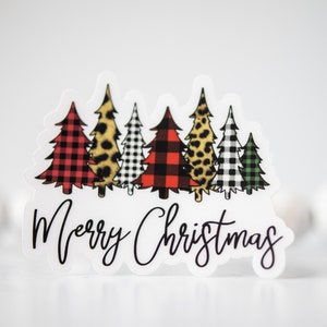 Puede incluir: Una pegatina blanca con una fila de cinco &aacute;rboles de Navidad en diferentes patrones. Los &aacute;rboles son de cuadros rojos y negros, estampado de leopardo, cuadros negros y blancos y cuadros verdes y blancos. El texto "Merry Christmas" est&aacute; escrito en cursiva negra debajo de los &aacute;rboles.