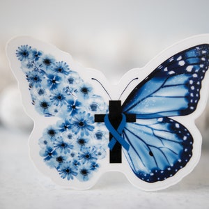May include: A blue butterfly sticker with a blue ribbon and a black cross. The butterfly is made up of blue flowers on one side and blue wings on the other.