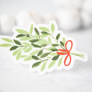 May include: A green mistletoe sprig with a red bow. The mistletoe is a traditional Christmas decoration.