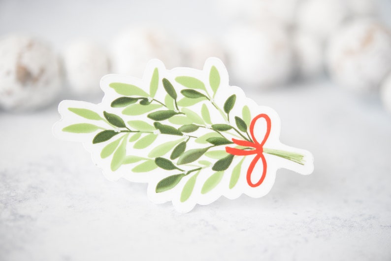 May include: A green mistletoe sprig with a red bow. The mistletoe is a traditional Christmas decoration.