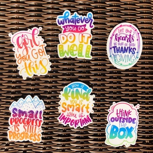 Puede incluir: Un conjunto de 7 pegatinas coloridas con frases motivacionales. Las pegatinas presentan degradados de arco&iacute;ris y letras escritas a mano. Las frases incluyen "Girl you got this", "Whatever you do, do it well", "Let our hearts be full of thanks giving", "You is kind, you is smart, you is important", "Small progress is still progress", y "Think outside the box".