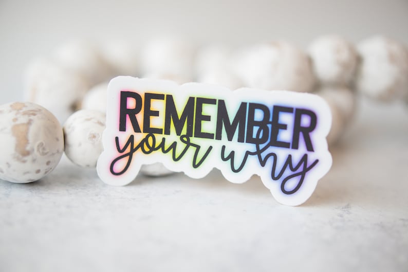 May include: A white sticker with a rainbow gradient behind the text "REMEMBER your why" in black.