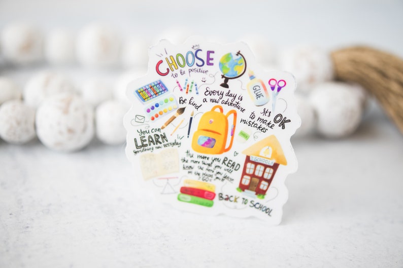 May include: A colorful sticker with a back to school theme. It features a yellow backpack, a schoolhouse, books, scissors, glue, paintbrushes, and a globe. The sticker has the text "Choose to be positive", "You can learn something new everyday", "Every day is a new adventure", "Be kind", "It's OK to make mistakes", "The more you read the more things you will know", and "Back to School".