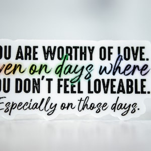 May include: White sticker with black text that reads "YOU ARE WORTHY OF LOVE. even on days where YOU DON'T FEEL LOVEABLE. Especially on those days."