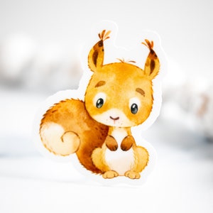 May include: A watercolor illustration of a cute, cartoon squirrel with a bushy tail. The squirrel is brown and orange with big, black eyes and a small, pink nose. The illustration is on a white background.