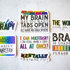 May include: Set of ten colorful stickers with humorous sayings about mental health and multitasking. The stickers feature rainbow colors and black text. The sayings include "Normalize Therapy", "My Brain Has Too Many Tabs Open", "The World Needs You In It", "Hello I'm Easily Distracted", "I Can Multitask! I Can Listen, Ignore & Forget All At Once!", "Mentally Checked Out", "Brain Is Loading... Please Wait".