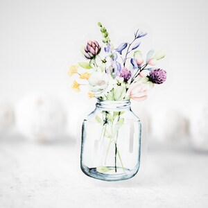 May include: A watercolor illustration of a bouquet of flowers in a clear glass jar. The flowers are in shades of purple, pink, yellow, and green.