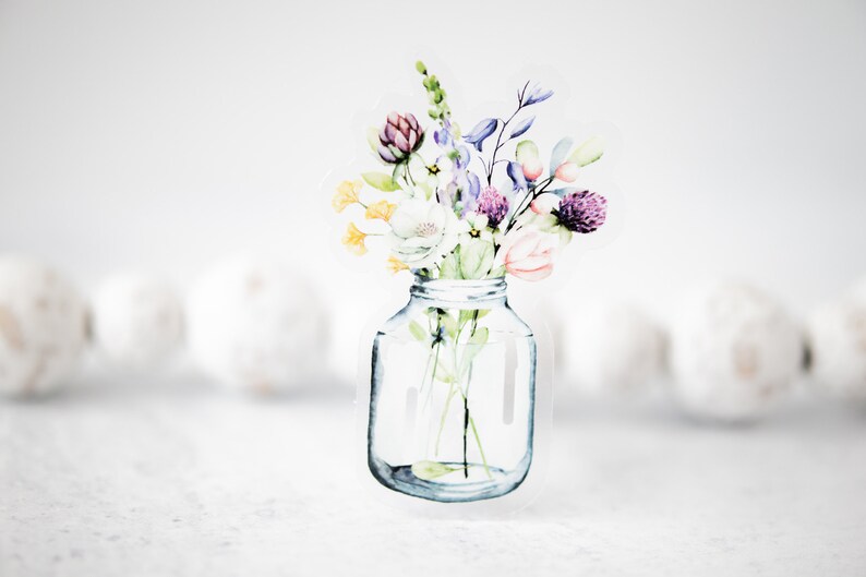 May include: A watercolor illustration of a bouquet of flowers in a clear glass jar. The flowers are in shades of purple, pink, yellow, and green.