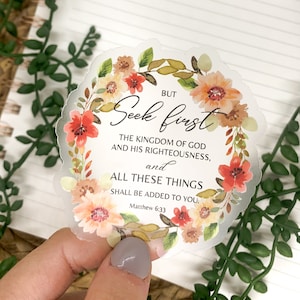 May include: A clear sticker with a floral wreath design and the text "BUT Seek first THE KINGDOM OF GOD AND HIS RIGHTEOUSNESS, and ALL THESE THINGS SHALL BE ADDED TO YOU. Matthew 6:33"