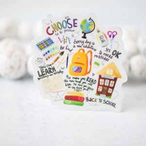 May include: A colorful sticker with a schoolhouse, backpack, and other school supplies. It has the text "Choose to be positive", "Every day is a new adventure", "It's OK to make mistakes", "You can learn something new everyday", "The more you read the more things you will know the more you will learn the places you've been on the places you'll go", and "Back to School".