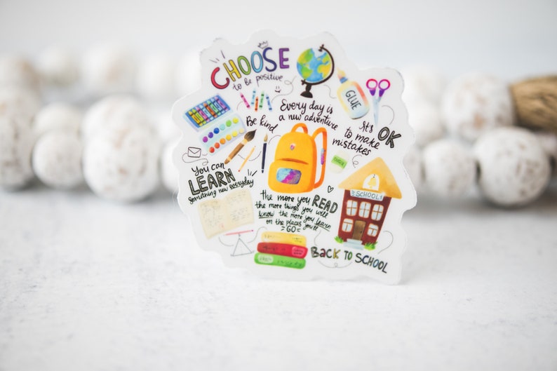 May include: A colorful sticker with a schoolhouse, backpack, and other school supplies. It has the text "Choose to be positive", "Every day is a new adventure", "It's OK to make mistakes", "You can learn something new everyday", "The more you read the more things you will know the more you will learn the places you've been on the places you'll go", and "Back to School".
