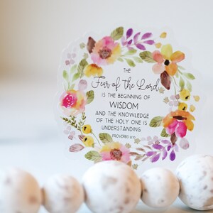 May include: A clear sticker with a watercolour floral wreath and the text "THE Fear of the Lord IS THE BEGINNING OF WISDOM AND THE KNOWLEDGE OF THE HOLY ONE IS UNDERSTANDING PROVERBS 9:10".