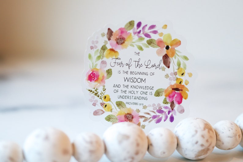 May include: A clear sticker with a watercolour floral wreath and the text "THE Fear of the Lord IS THE BEGINNING OF WISDOM AND THE KNOWLEDGE OF THE HOLY ONE IS UNDERSTANDING PROVERBS 9:10".