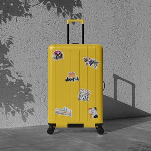 May include: A bright yellow rolling suitcase with a retractable handle and several travel-themed stickers. The suitcase is standing upright on a tiled surface, with a textured wall and shadows in the background. The stickers include the words "Beach" and "Joy".