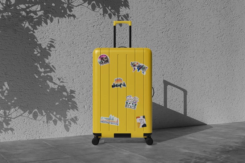 May include: A bright yellow rolling suitcase with a retractable handle and several travel-themed stickers. The suitcase is standing upright on a tiled surface, with a textured wall and shadows in the background. The stickers include the words "Beach" and "Joy".