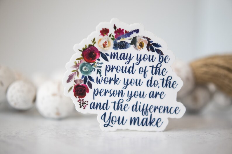 May include: A white sticker with a floral design and the text "may you be proud of the work you do, the person you are and the difference you make".