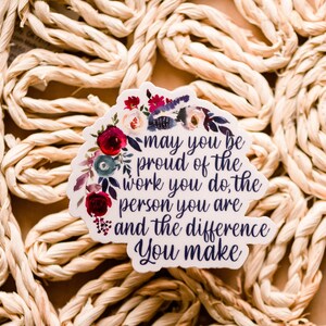 May include: A white sticker with a floral design and the text "may you be proud of the work you do, the person you are and the difference you make".