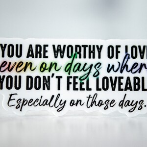 May include: White sticker with black text that reads "YOU ARE WORTHY OF LOVE. even on days where YOU DON'T FEEL LOVEABLE. Especially on those days."