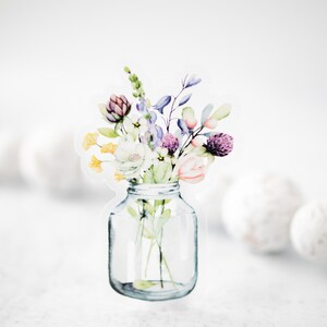 May include: A watercolor illustration of a bouquet of flowers in a clear glass jar. The flowers are in shades of pink, purple, yellow, and green.