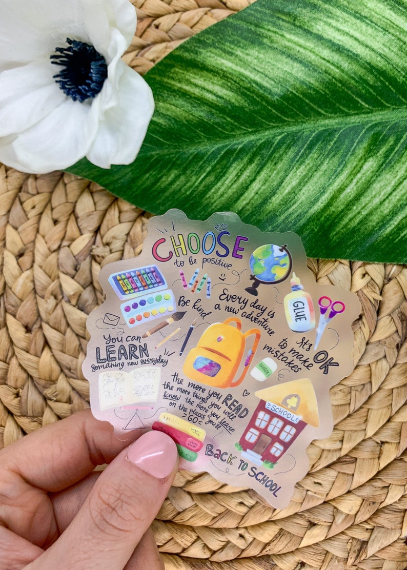 May include: A gold sticker with a back to school theme. It features illustrations of school supplies, a backpack, a school building, and a globe. The sticker has the text "Choose to be positive", "Every day is a new adventure", "You can learn something new everyday", "Be kind", "It's OK to make mistakes", "The more you read the more things you will know the more you learn on the places you'll go", and "Back to school".