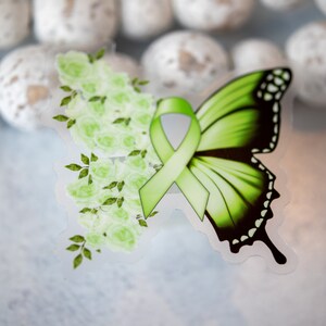 May include: A green butterfly with a green ribbon tied around it. The butterfly is surrounded by green flowers.