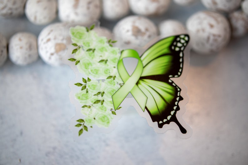 May include: A green butterfly with a green ribbon tied around it. The butterfly is surrounded by green flowers.
