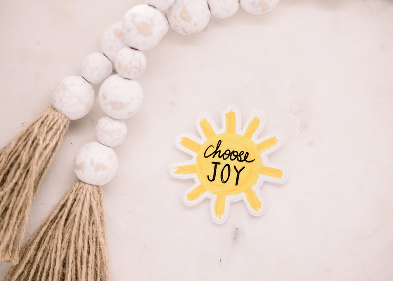 May include: A yellow sun sticker with the words "choose JOY" written in black.