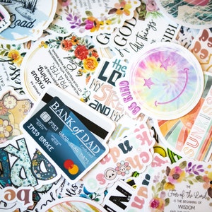 May include: A collection of colorful stickers with various designs and phrases, including "Be Kind", "Fear of the Lord is the beginning of wisdom", "I'm Unsuper", "How Blessed to be", "Pray", "Go Kind", "My Strength", "Bank of Dad", and "Sun Kissed".