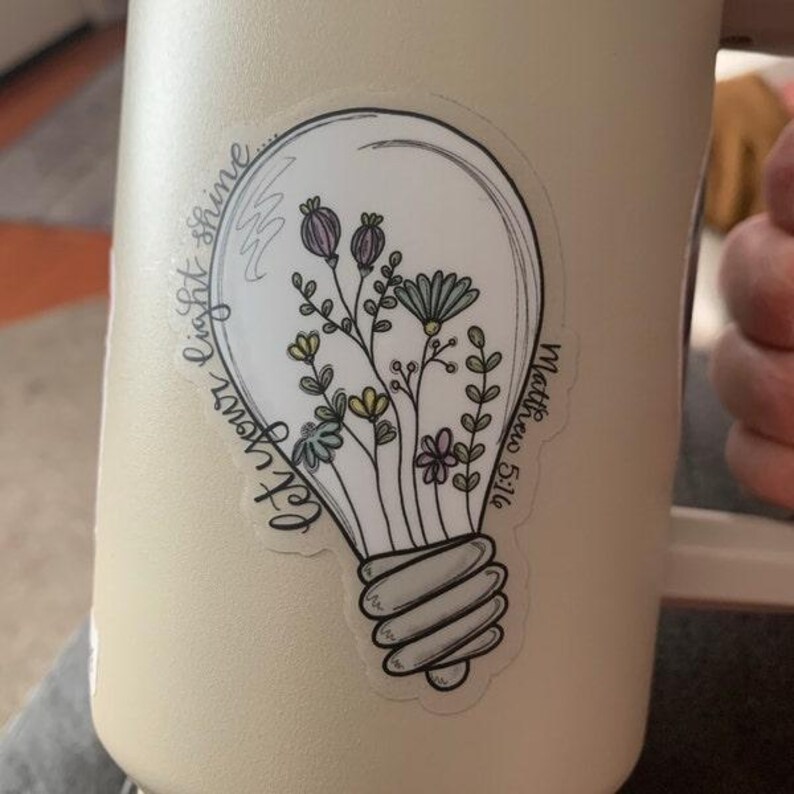 May include: A white lightbulb sticker with a floral design and the text "Let your light shine" and "Matthew 5:16".