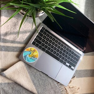May include: A laptop computer with a sticker that says "Salt & Light" on a striped blanket. The sticker has a wave design and a yellow sun.