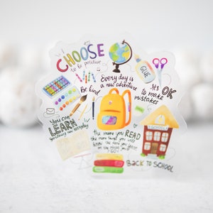 May include: A colorful back to school sticker with a schoolhouse, backpack, globe, and other school supplies. The sticker has the text "Choose to be positive", "Every day is a new adventure", "Be kind", "You can learn something new everyday", "It's OK to make mistakes", "The more you read the more you will know the more you will learn", and "Back to school".
