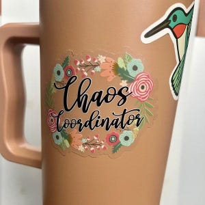 May include: A brown mug with a floral sticker that says "Chaos Coordinator".