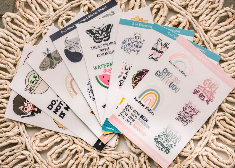 May include: A set of colorful sticker sheets with various designs and inspirational quotes. The stickers feature butterflies, rainbows, watermelons, and other cute illustrations. The quotes include "Treat people with kindness", "Choose gratitude", and "Every moment is a fresh begining".