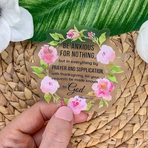 May include: A gold sticker with a floral design and the text "BE ANXIOUS FOR NOTHING, but in everything by PRAYER AND SUPPLICATION, with thanksgiving, let your requests be made known to God Philippians 4:6".