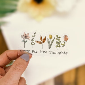 May include: Clear sticker with a line drawing of flowers and the text "Grow Positive Thoughts".