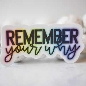 May include: A white sticker with a rainbow gradient background and black text that reads "REMEMBER your why".