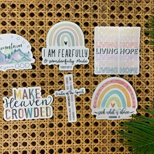 May include: Six colorful stickers with religious quotes and designs. The stickers feature rainbows, mountains, a cross, and the words "Living Hope", "I am fearfully and wonderfully made", "Tell your mountain about your God", "Make Heaven Crowded", and "Seek what is above".