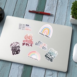 Puede incluir: Un conjunto de siete pegatinas coloridas con citas inspiradoras y dise&ntilde;os de arco&iacute;ris. Las pegatinas incluyen citas como "S&eacute; la chica que decidi&oacute; ir a por ello", "Elige la gratitud", "&iquest;Qu&eacute; pasa si me caigo? Pero &iquest;qu&eacute; pasa si vuelo?" y "Debajo de las estrellas todos somos so&ntilde;adores".